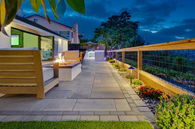 Path lights and river-rock borders glow along the side yard at dusk