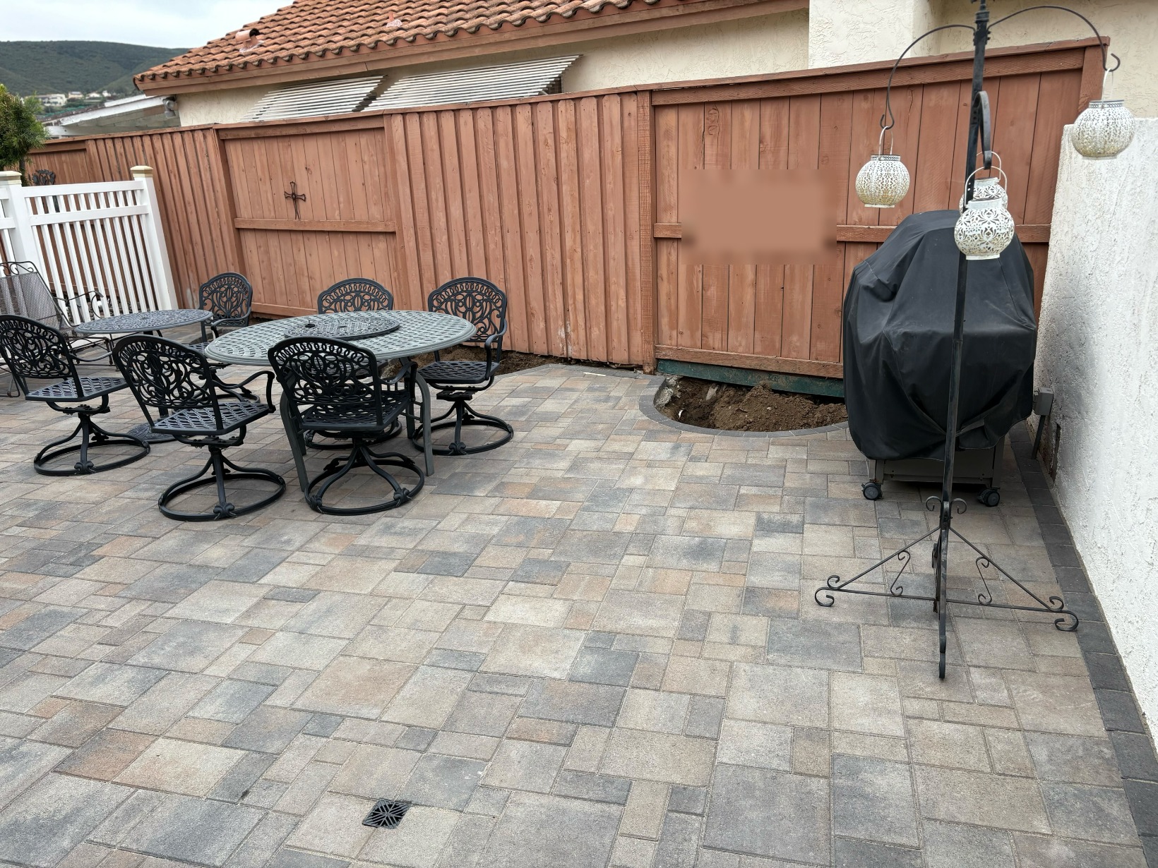 The completed patio from the grill side, the flush drain grate visible mid-field where the SDR35 line carries runoff away from the house.