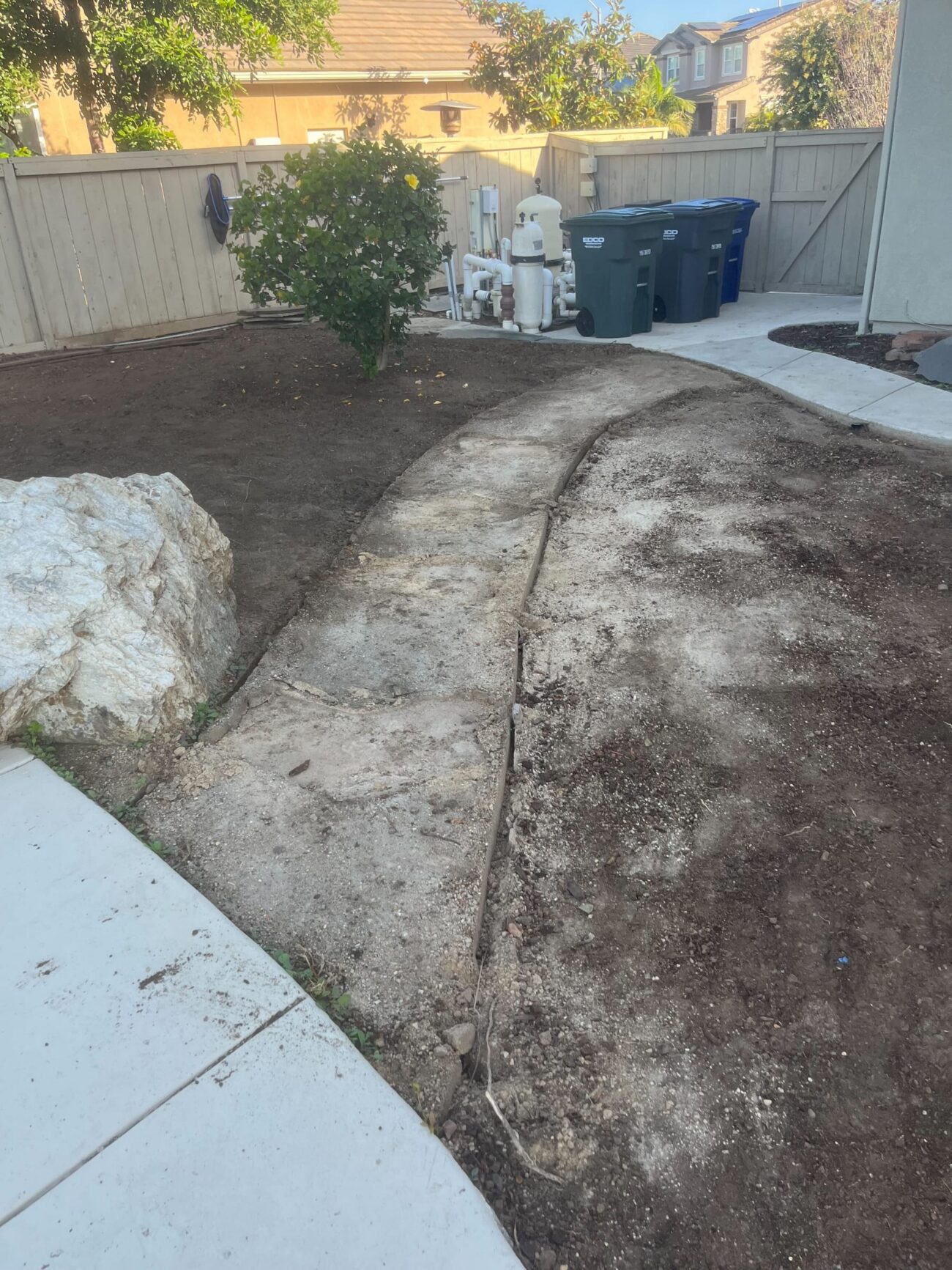 Curved walkway and lawn area opened up during demolition before the new turf and paver layout.