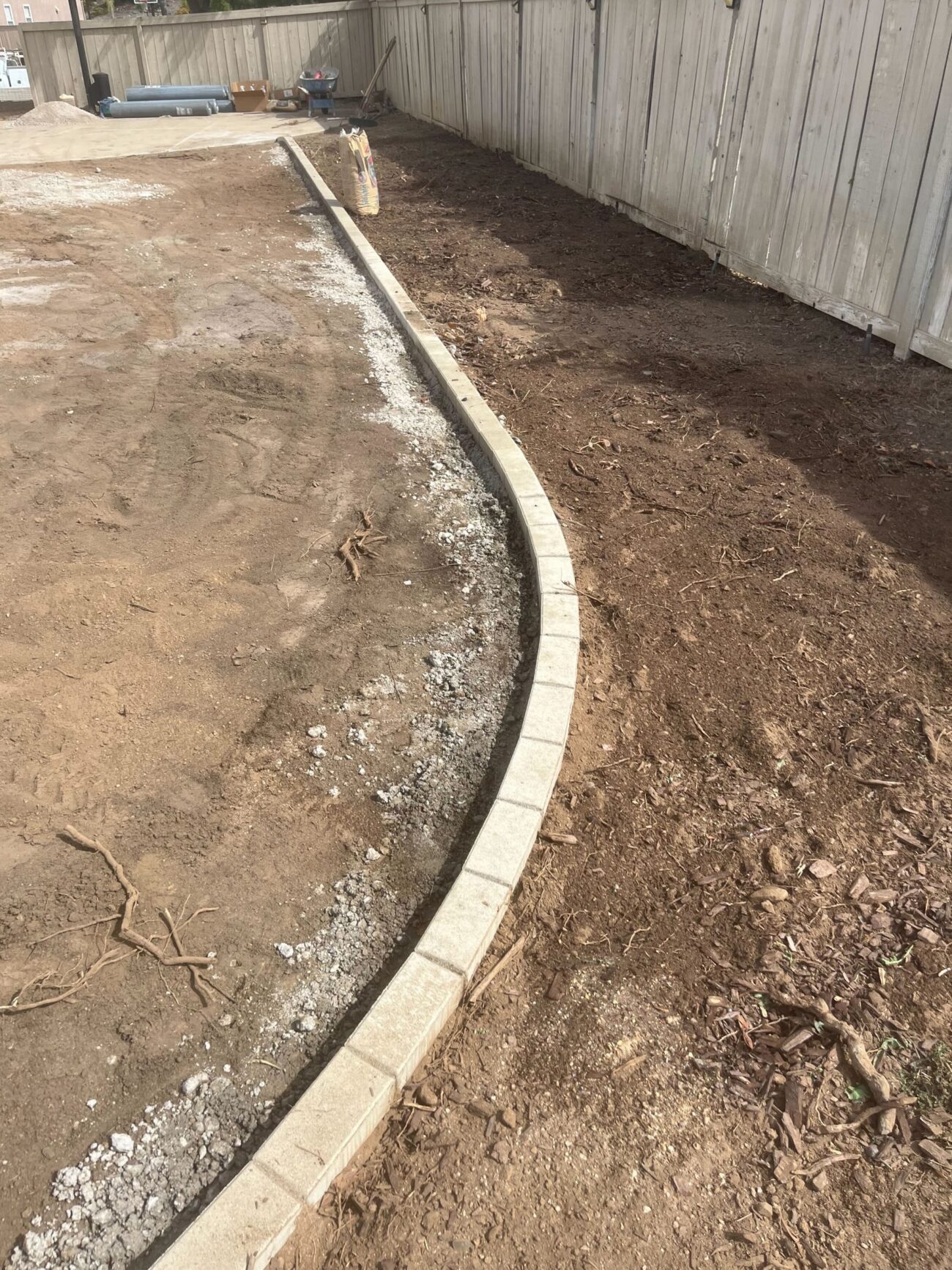 Curved paver border being set against the prepared base before final infill and cleanup.