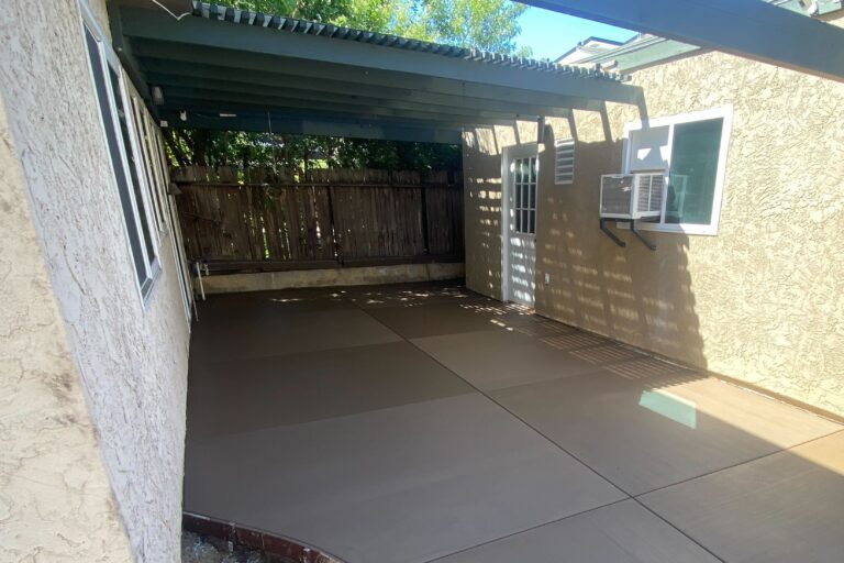 Cropped view of colored concrete patio with saw-cut control joints under the existing pergola in Tierrasanta.