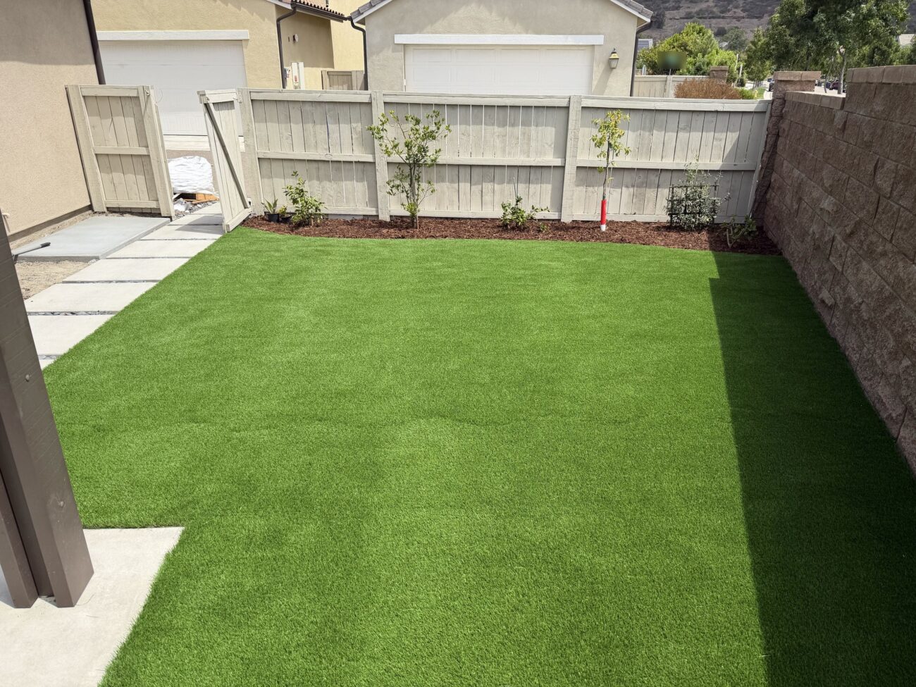 Backyard turf lawn with new shrubs and small trees in mulched beds along the fence, Escondido 92029