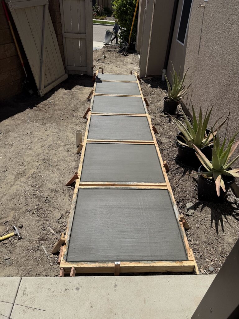 Concrete step pads freshly poured in wood forms along the side yard, Escondido 92029