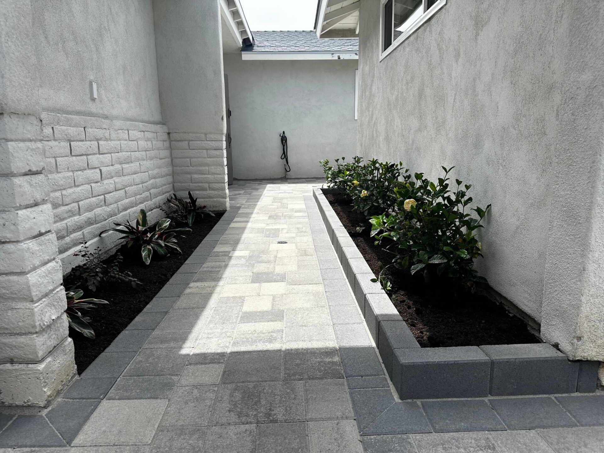 Angelus pavers between two wings of the house, with planter beds edged in pavers set on end