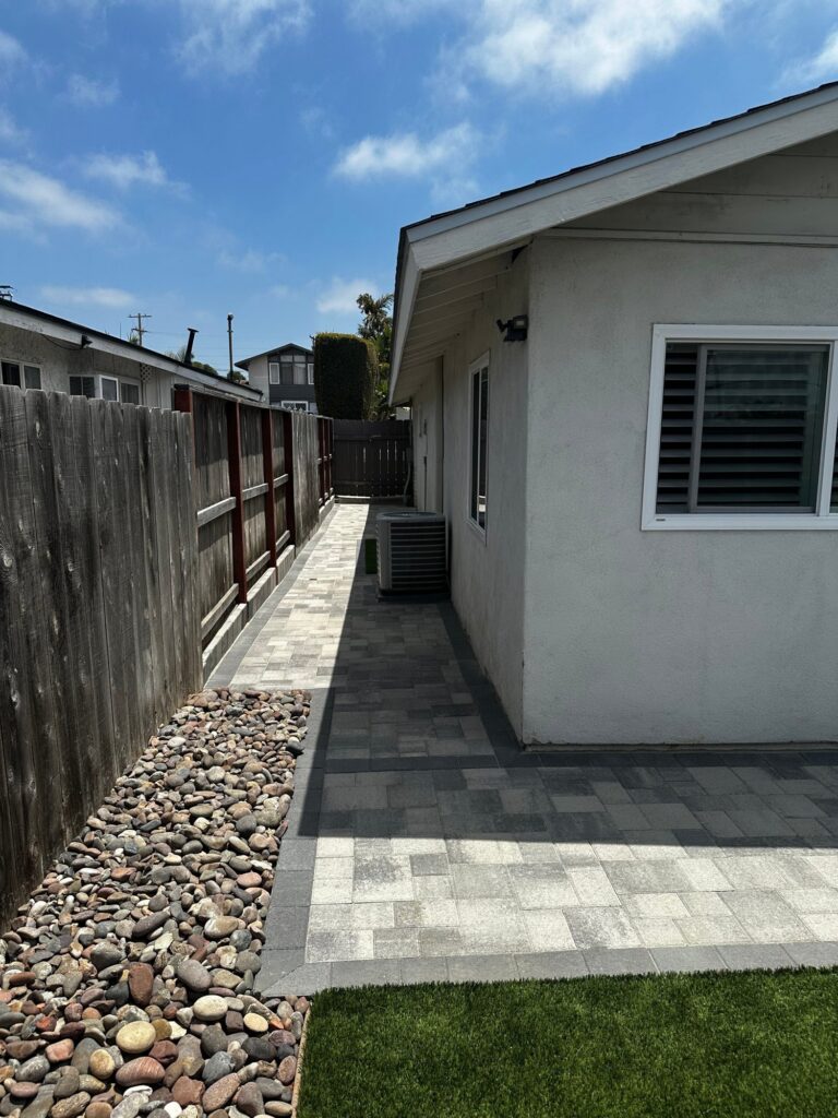 Pavers beside the river rock bed at the back corner of the house