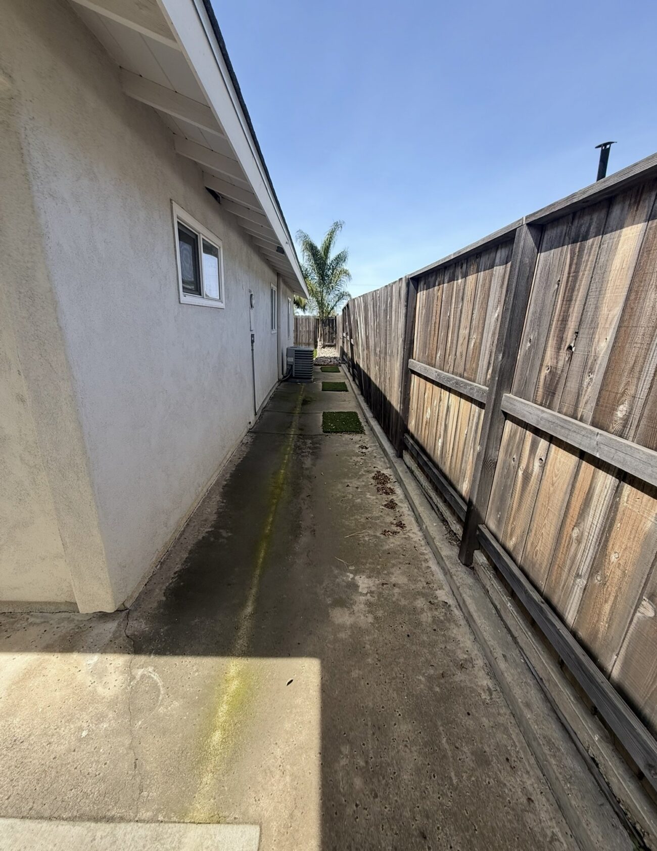 Before: concrete and loose turf mats along the fence