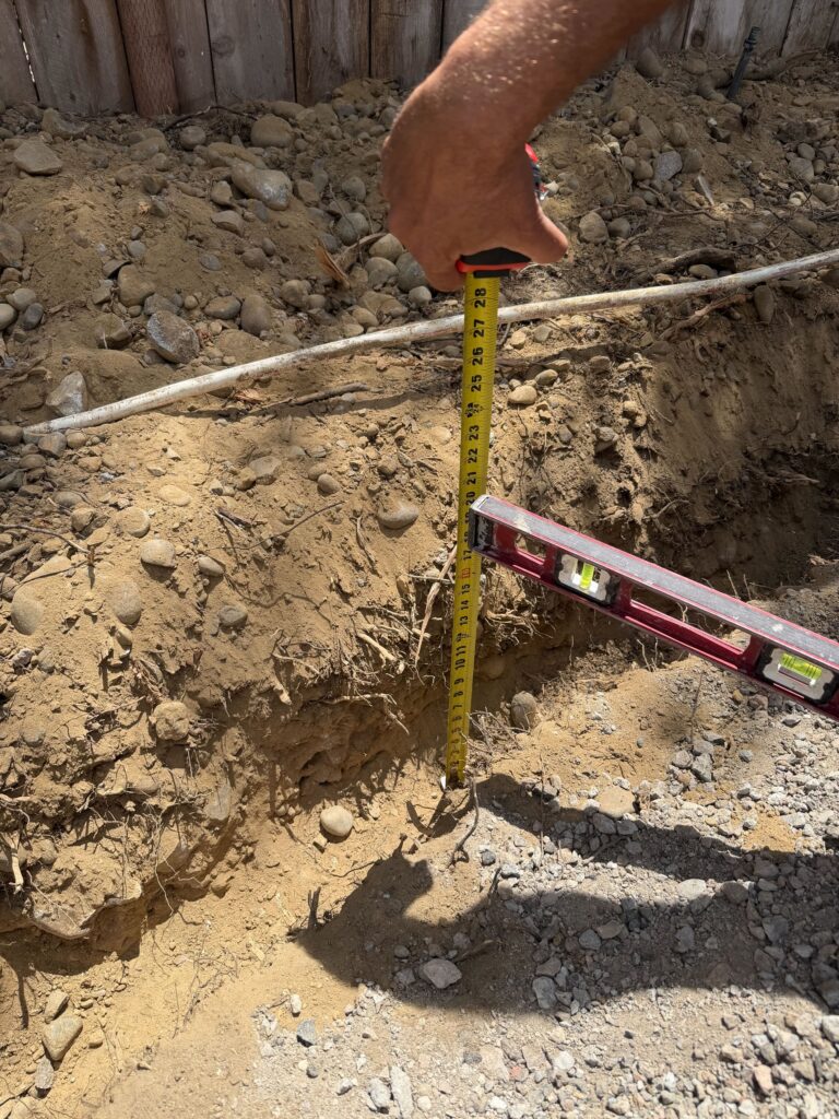 Build stage: turf excavation depth checked with a tape and level before base went in