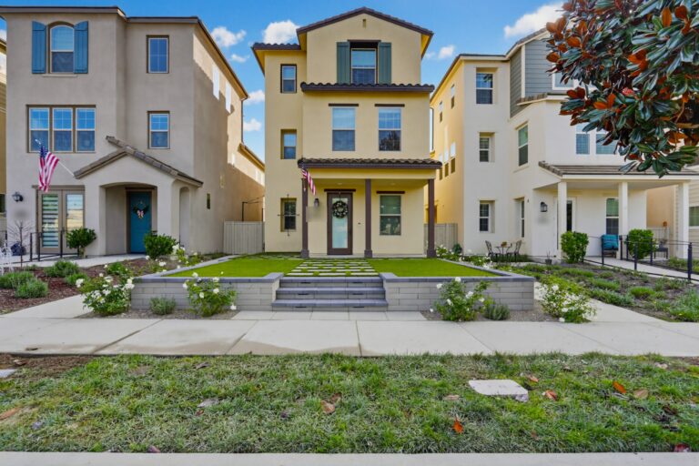 Straight-on front elevation: paver steps and the inset-paver walk centered on the entry, the turf lawn raised behind the Bastione retaining wall.